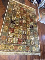 Angled full-view of the rug on a hardwood floor showing overall pattern and fringe