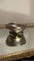 Side view showing the ornate floral embossed pattern around the rim and the three feet supporting the candy dish.