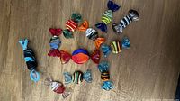 Photo of 12 Murano glass candy figurines arranged on a wooden surface showing various colors and stripe patterns.