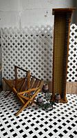 Photo showing wooden child's chair, tall wooden wall rack, ceramic planters, and green metal plant holders against lattice background