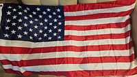 Image of a large American flag laid flat to show full design and condition.