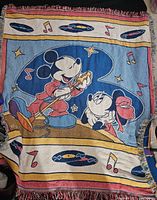 Woven throw blanket with Mickey Mouse singing into a microphone and Minnie Mouse listening, surrounded by music notes and vinyl records.