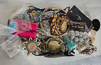 Photo shows a collection of assorted jewelry including various bracelets, bangles, beads, and other small jewelry pieces in a bag with some vintage style buttons visible.