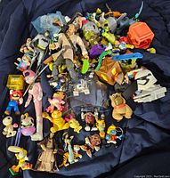 Wide view of the lot showing a pile of mixed vintage and modern toys including Batman, Mario, Scooby-Doo, and various others.