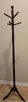 Full length photo of the cherry finished wooden coat rack with multiple peg hooks and turned design on the pole
