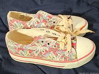 Side angled view of the floral lace Crayons sneakers showing both shoes side by side, emphasizing the lace design and cream laces.