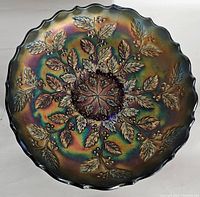Top view photo showing round carnival glass bowl with scalloped edges and raised floral leaf design in iridescent colors.