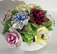 Top angled view of the Royal Doulton bone china bouquet showing the dark red rose, white and yellow flowers, blue carnation, pink rose, and green leaves.