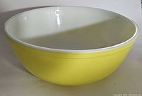 Front and side view of the yellow Pyrex Primary mixing bowl showing exterior yellow color and white interior.