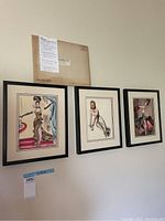 Photo showing three framed vintage art pieces of Ziegfeld Follies girls hanging on a wall with an original mailing envelope pinned above them.