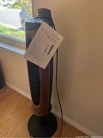 Front and side view of tower fan with wood grain finish and control buttons on top, showing the fan design.