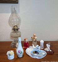 Lot of decorative items including clear glass hurricane lamp, small porcelain vase with floral design, porcelain flower-topped jewelry box, Willow Tree Serenity figurine, white porcelain jewelry dish with small decorative spheres, and several small ceramic figurines