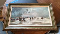 Full view of the framed oil painting showing fishermen and boats on the beach with cloudy sky.
