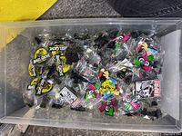 Clear plastic container with individually bagged enamel collector pins of various themes including Angel Grove and Star Wars Empire.