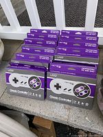 Photo of 12 new Retron Home Classic Controller boxes arranged in two rows showing front packaging with graphics and wearable boxes.