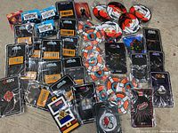 Photo showing 43 enamel collector pins laid out on a surface. Various circular and shaped pins, mostly new and mounted on branded backing cards, including several with the Outatime license plate design and IGN brand cards.