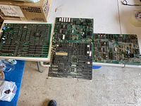 Four arcade PCB boards arranged on white surfaces, showing layout and component density