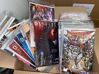 Photo showing multiple comic books in a box, all individually sealed in plastic bags with backing boards, front covers visible with titles including 'Aliens Defiance' and 'Bebop & Rocksteady'.