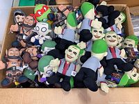 Wide view of a box filled with various plush character toys including multiple Joker figures, Teenage Mutant Ninja Turtles, and other cartoon and comic style characters in new condition.