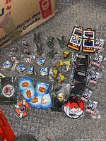 Overall view of all enamel pins spread out on carpet, showing various designs and packaging.