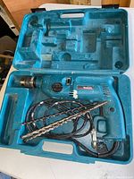 Makita HP2040 hammer drill in blue plastic case with two long drill bits and power cord visible