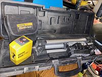 Photo of open carrying case showing laser level, tripod, and soft pouch inside.