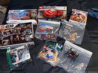 Top view showing opened LEGO set boxes including Star Wars, Speed Champions Ferrari, and Marvel Captain America, with multiple plastic bags with assorted LEGO pieces and minifigures