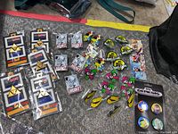 Full lot overview showing all enamel collector pins arranged on a surface, new condition, still in packaging for some pins.