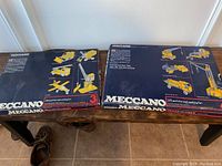 Two original Meccano boxes side by side showing Meccano 3 with 200 parts and Meccano 4 with 275 parts