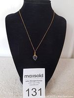 Full view of the black onyx heart pendant on a gold chain displayed on a black jewelry bust.