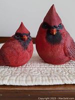 Close-up front view of the two red cardinal figurines showing detailed texture and paint.