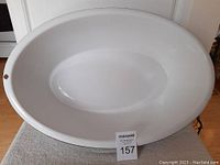 Top-down view of large white oval enamel baby bathtub showing interior surface