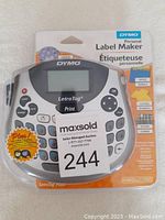 DYMO LetraTag Plus label maker in original sealed packaging, front view showing keyboard and display.