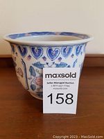 Front view of white ceramic flower pot with blue heart and pink floral designs, slightly flared rim