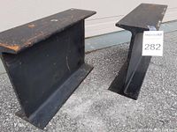 Two solid steel I-beams standing upright on concrete, showing overall size and shape.