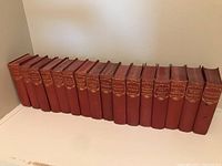 Full row of 17 red cloth–bound Dickens volumes on shelf