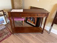 Wooden console table with two drawers, turned legs, and lower shelf, showing original assembly instructions on top.