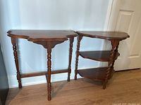 Front view of two wooden demi tables; one has flat top and the other has two crescent shelves under the top
