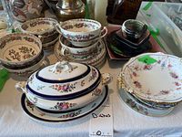Wide view of assorted dishes and servers including covered serving dish, teacups, bowls with floral designs