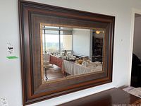 Front view showing the full rectangular mirror with layered wood frame in various brown tones and beveled glass edges.