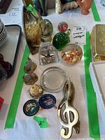 Overview of paperweights, metal door knocker, and figurines arranged on table