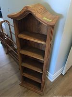 Front angled view showing five shelves, curved top, and wood grain texture.