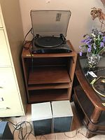 ION turntable on wooden shelving unit with Toshiba speakers below.