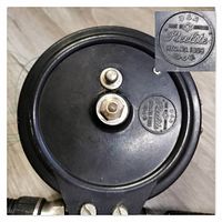Close-up photo of black bakelite vintage fishing reel showing Steelite brand, model number 364, made in Australia embossing on reel spool, with reel hardware and fishing line visible.