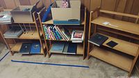 Wide view of three wooden shelves holding numerous books including large hardback art and yearbooks, with some books stacked.