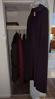 Coats hanging in closet with wool cape in front