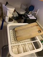 Overview photo showing Melitta coffee maker, Amazon Basics toaster, plastic storage containers, dish drainer and wooden cutting board on countertop.