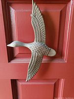Front view of bronze bird door knocker mounted on a red door.
