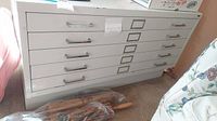 Front view of metal filing cabinet showing five drawers with label holders and silver handles.