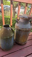 Both vintage metal milk cans shown together, displaying size and condition